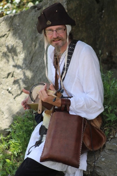 Homme dans la nature en costume de barde avec un instrument traditionnel à corde.